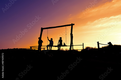 people sitting on the swing with beautiful sunset in farm