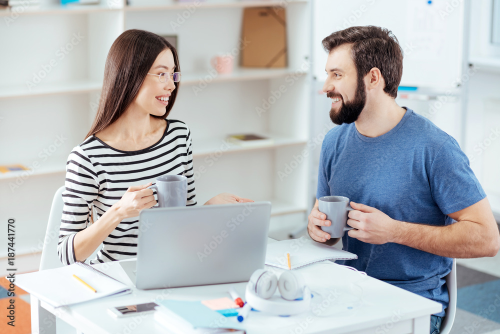 Coffee break. Merry play two colleagues looking at each other and laughing while drinking coffee Coffee break. Merry play two colleagues looking at each other and laughing while drinking coffee