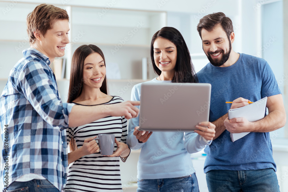 Minor typos. Energetic optimistic four colleagues searching for solution while looking at the screen and woman using laptop Minor typos. Energetic optimistic four colleagues searching for solution while looking at the screen and woman using laptop