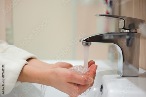 Fototapeta Naklejka Na Ścianę i Meble -  A woman washing her hands in the sink
