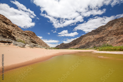 Panoramic view of rests of water during dry season near Ai-Ais Hot Springs at the base of the mountain peaks at the southern end of Fish River Canyon, in the Karas Region of southern Namibia, Africa.
