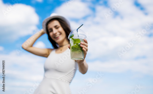 Will you have a refreshing cocktail? Cheerful beautiful girl in a white hat with a cold mojito in hands. Summer rest © My Ocean studio