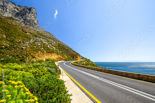Stunning view of Route 44 in the eastern part of False Bay near Cape Town between Gordon's Bay and Pringle Bay. Hottentots Holland Mountain range in the background. Beautiful flowers on the left. photo