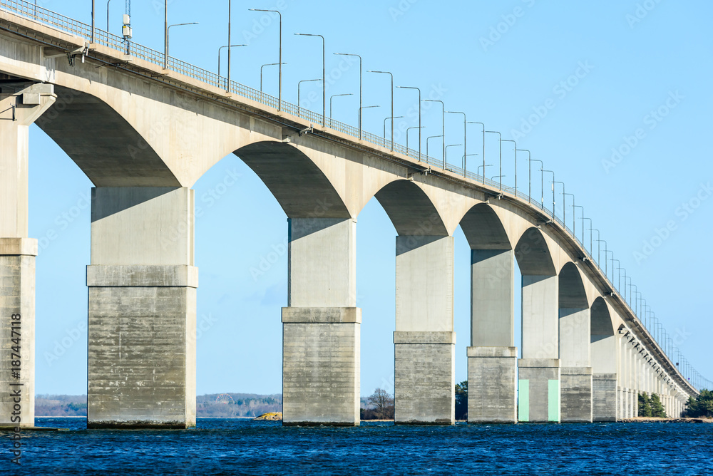 Concrete bridge over water. Gray pillars support the weight of the