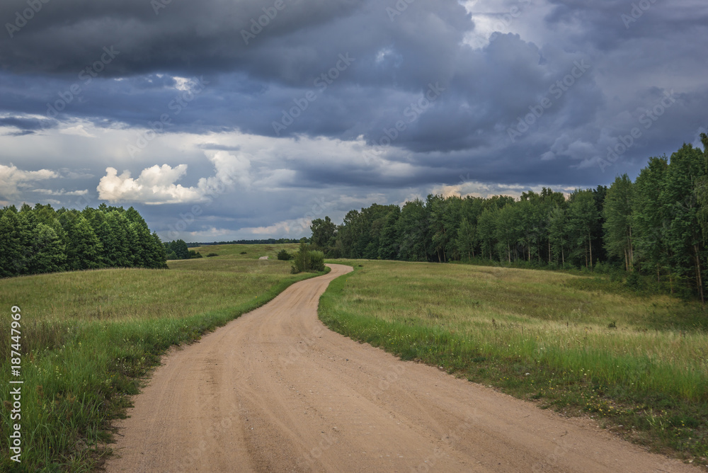 Dust road among meadows in Masurian Lakeland region of Poland