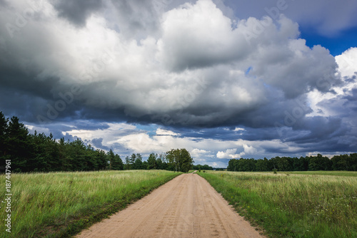 Fototapeta Naklejka Na Ścianę i Meble -  Dust road among meadows in Masurian Lakeland region of Poland