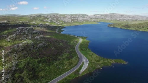 Backward flight away from hight mountain road over small pond in Australian Alps in summer