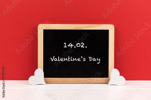blackboard with hearts and red background with text 14.02. Valentine's Day