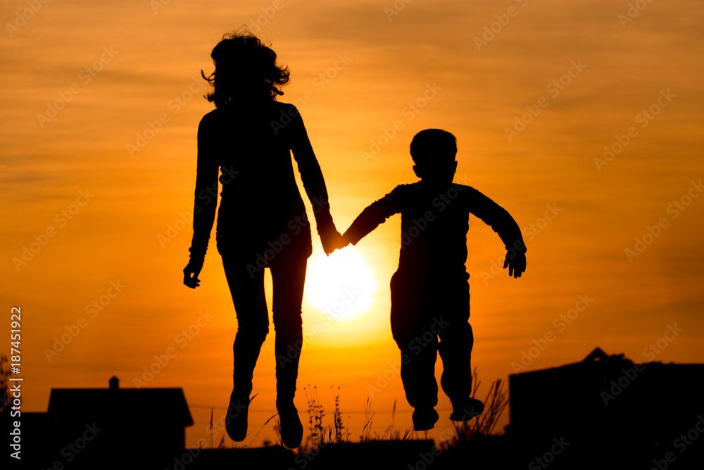 Silhouette of Mom and son in the rays of sunset