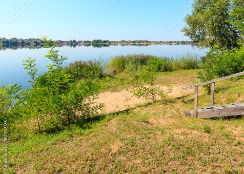 Summer lake calm beach with wood steeps to the water