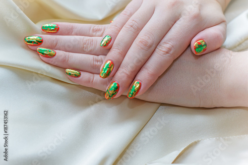 A bright manicure with gold and green glitter on the nails. Hand care and for yourself. Beauty for Women 