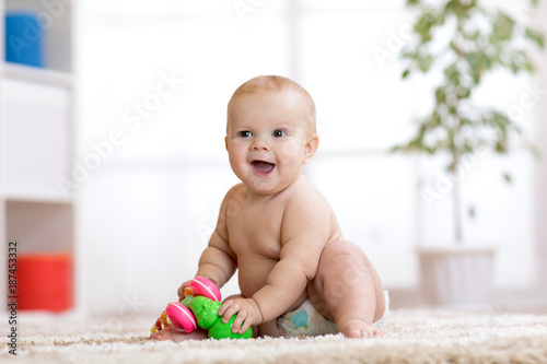 Funny baby in diaper sits o...