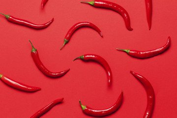 Red chili peppers arranged on a bright red background