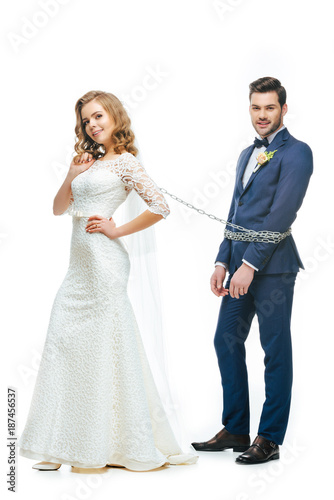 young bride holding groom on chain isolated on white