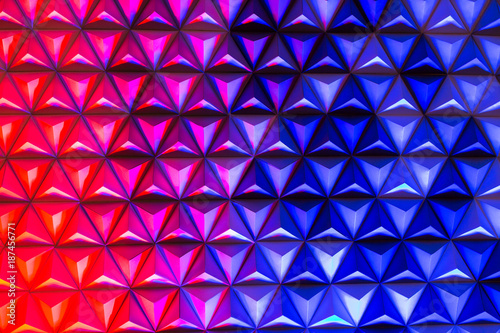 backdrop, architecture, decoration concept. blue and red coloures are mixing on the rough surface of wall covered with paper pyramids, these colores are creating lilac one