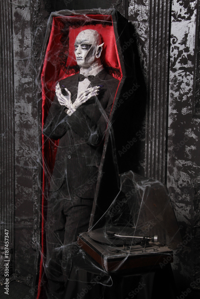 the halloween coffin with the dead vampire puppet of a man standing near the wall in a black