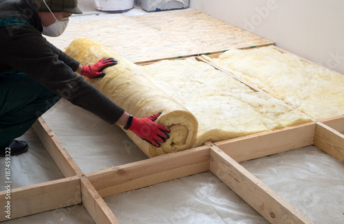 Work composed of mineral wool insulation in the floor, floor heating insulation , warm house, eco-friendly insulation, a builder at work