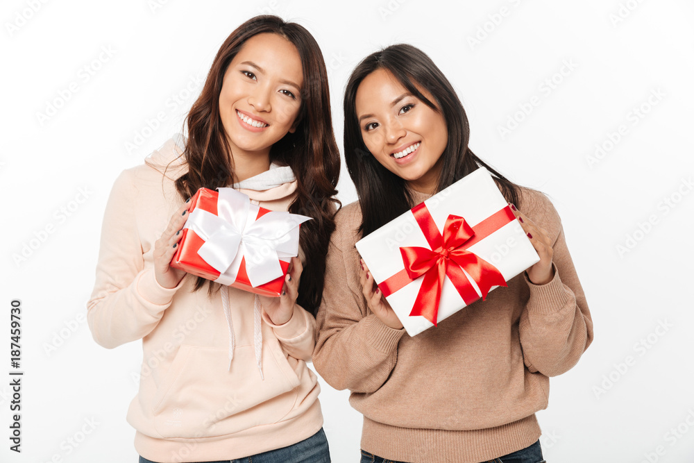 Fototapeta premium Two asian cute ladies sisters holding gift boxes surprise.
