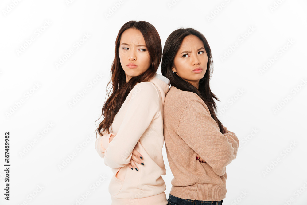 Asian angry ladies sisters standing isolated Asian angry ladies sisters standing isolated