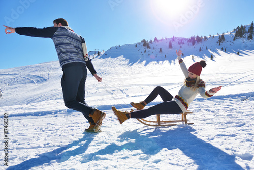 Young Couple Sledding And Enjoying On Sunny Winter Day