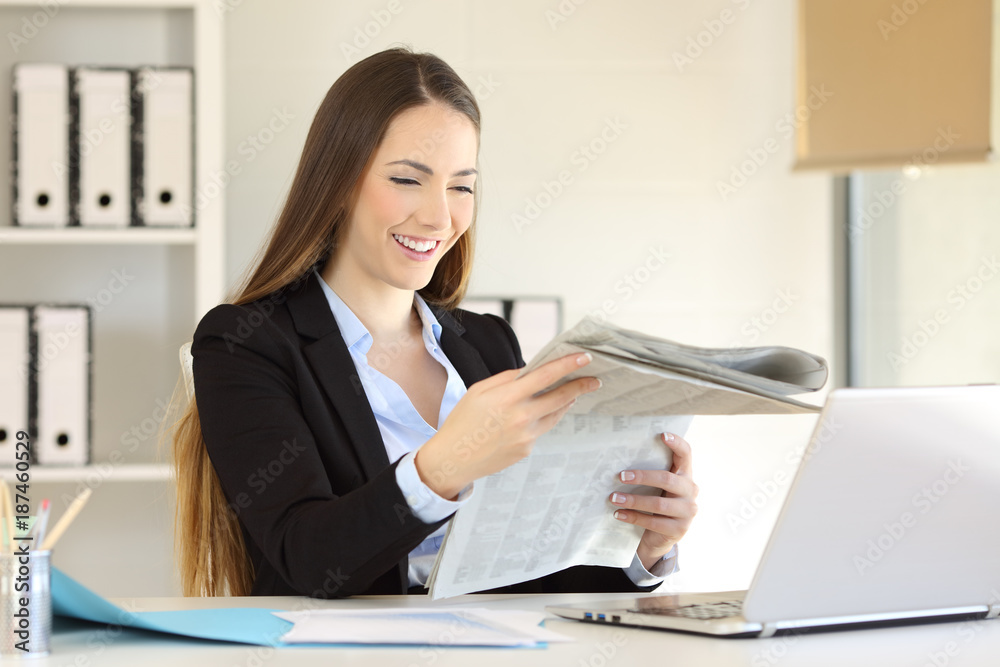 Happy executive reading a newspaper at office Happy executive reading a newspaper at office