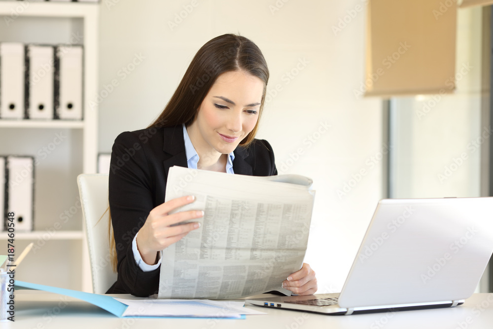 Businesswoman reading a newspaper at office Businesswoman reading a newspaper at office