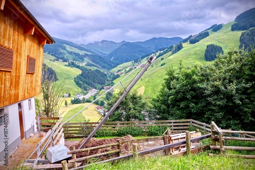 Barn with wire rope hoist over a dung and green alpine peaks in Saalbach, Austria photo