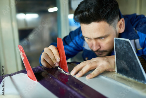 Photography Portrait of mature handsome man  carefully placing fins on custom surfing board