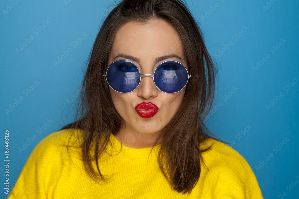 beautiful smiling woman with blue sunglasses and yellow blouse making a faces beautiful smiling woman with blue sunglasses and yellow blouse making a faces