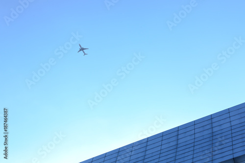 Airplane flying above glass office buildings and futuristic design
