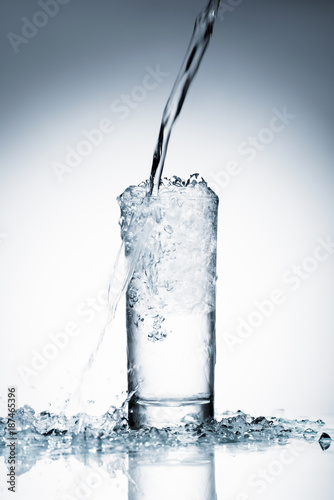 close-up shot of water pouring into glass on white