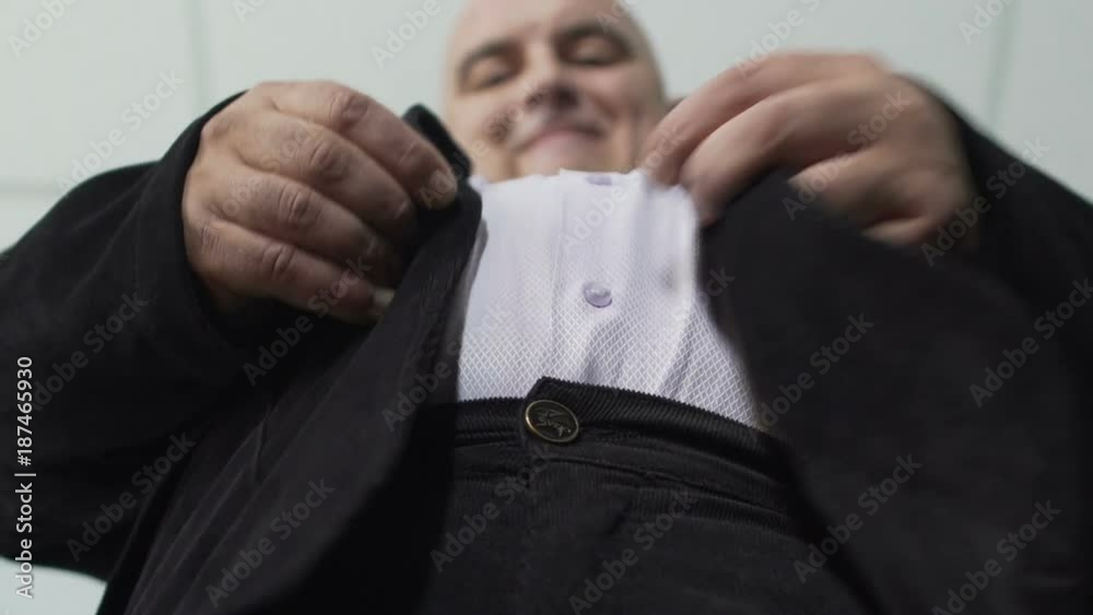 Fat man trying to fasten a button on his jacket, extra weight, bottom view Fat man trying to fasten a button on his jacket, extra weight, bottom view