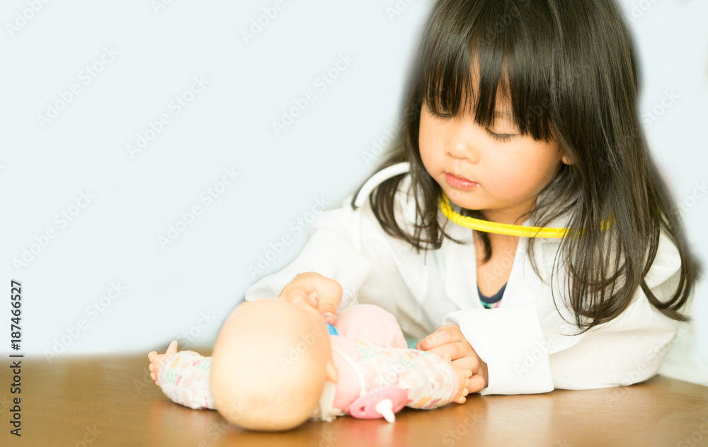 Little asian girl play with baby doll toy.Little asian girl hold stethoscope in hand and check baby doll toy. Little asian girl play with baby doll toy.Little asian girl hold stethoscope in hand and check baby doll toy.