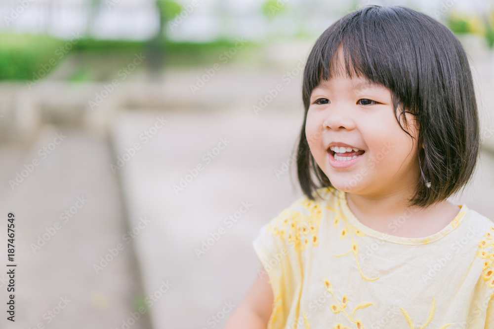 Little asian girl smiling with perfect smile and white teeth in a park and looking at camera.Little girl child showing front teeth with big smile.Joyful portrait of asian elementary school student. Little asian girl smiling with perfect smile and white teeth in a park and looking at camera.Little girl child showing front teeth with big smile.Joyful portrait of asian elementary school student.