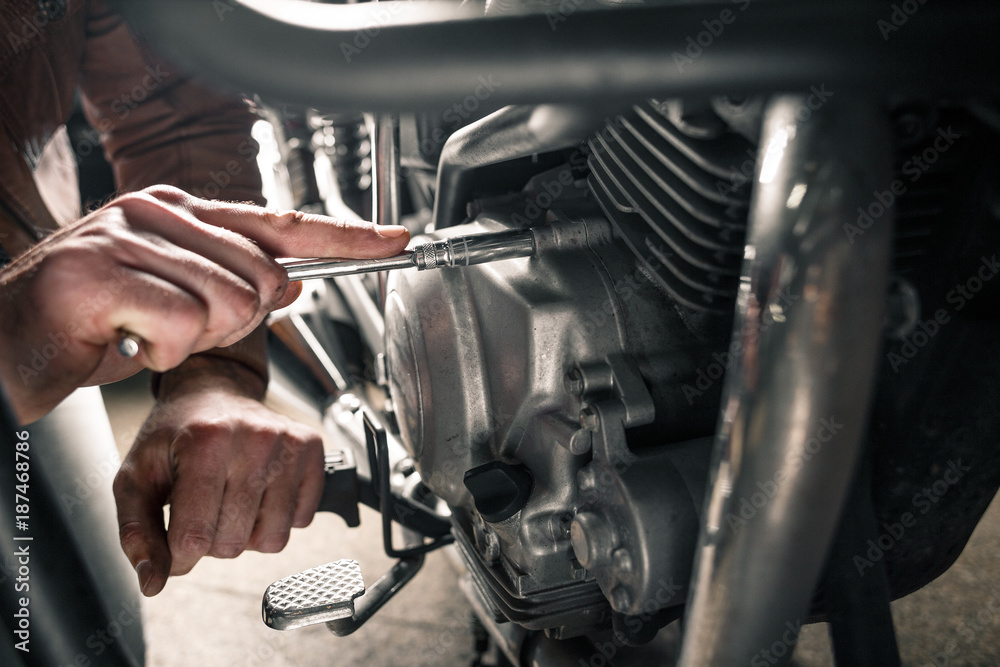 Fototapeta premium Zamyka up mężczyzna ręki naprawianie motocykl