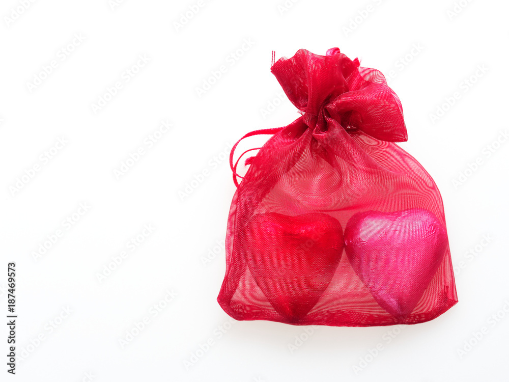 Heart shape chocolate wrapped in red and pink foil in red pouch isolated over white background Heart shape chocolate wrapped in red and pink foil in red pouch isolated over white background