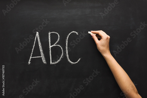 Woman writing abc on black chalkboard photo