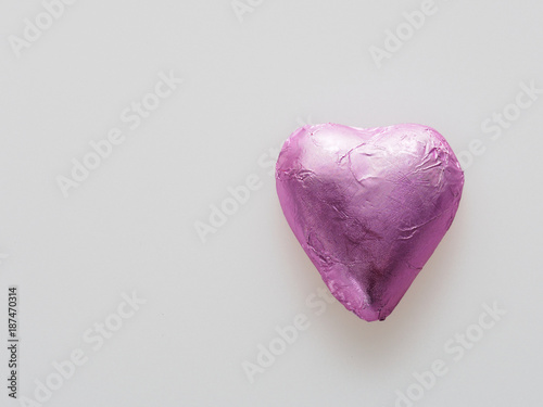 Heart shape chocolate wrapped in pink foil isolated over white background