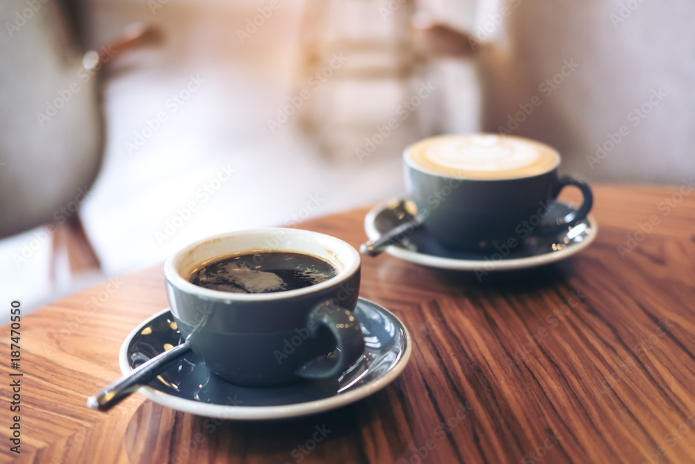 Fototapeta Zbliżenie obrazu dwóch niebieskich filiżanek gorącej kawy latte i kawy Americano na vintage drewnianym stole w kawiarni