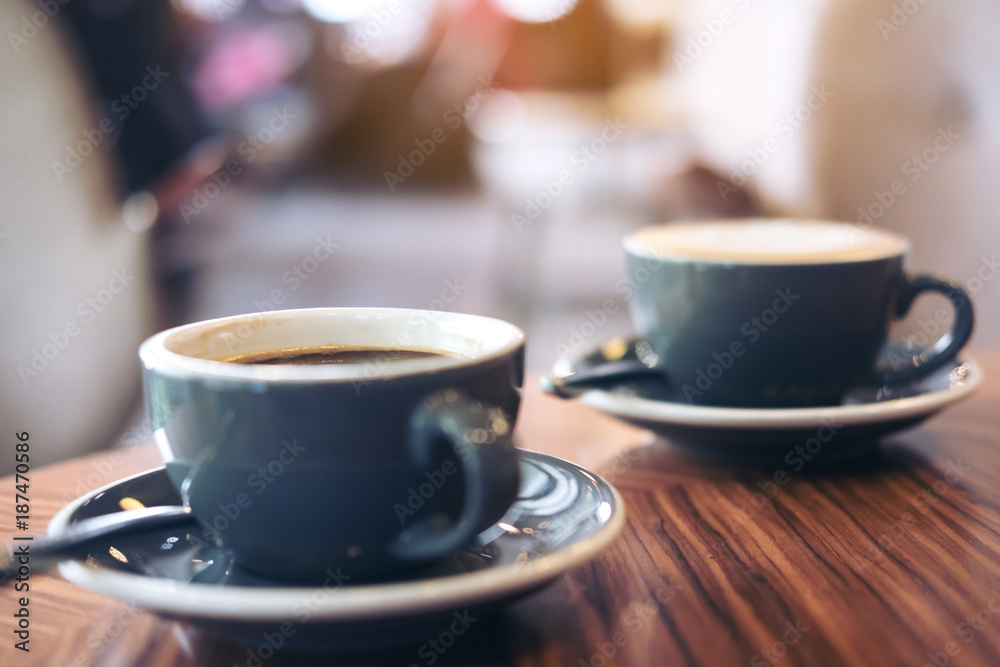 Fototapeta Closeup image of two blue cups of hot latte coffee and Americano coffee on vintage wooden table in cafe