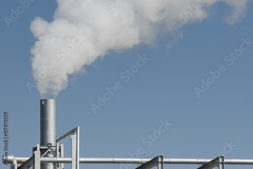 industrial fog from exhaust tube against blue sky background