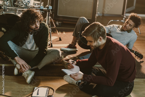 young music band writing lyrics together while sitting on floor