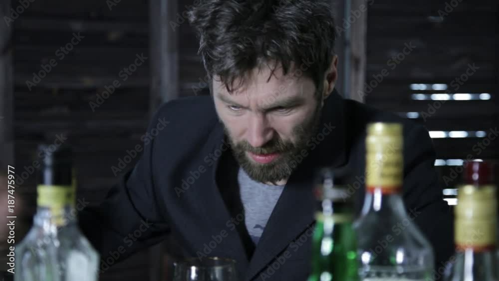 drunk man drinks alcohol, lot of empty bottles around him