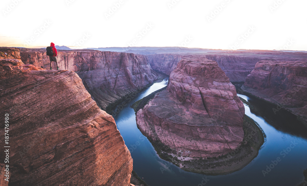 Hiker overlooking Horseshoe Bend at sunset, Arizona, USA