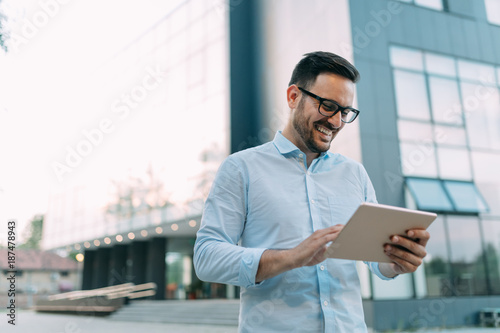 Portrait of businessman in glasses holding tablet
