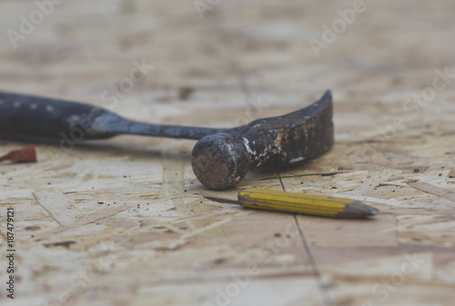 Builders hammer and pencil on wooden board