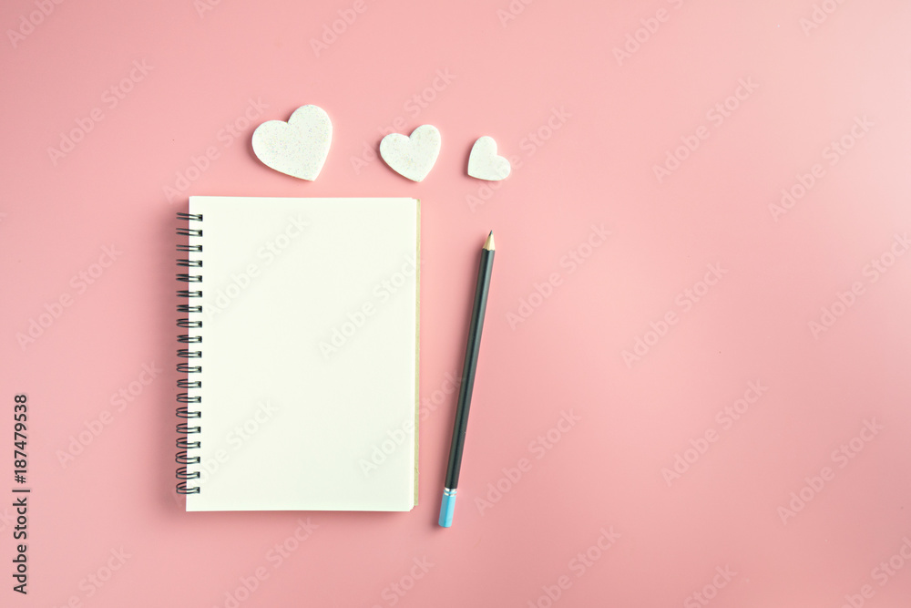 Top view of blank notebook pencil and hearts on pink background with copy space. Top view of blank notebook pencil and hearts on pink background with copy space.