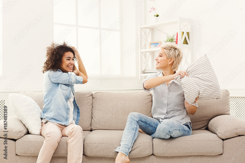 Two young women having pillow fight on sofa Two young women having pillow fight on sofa