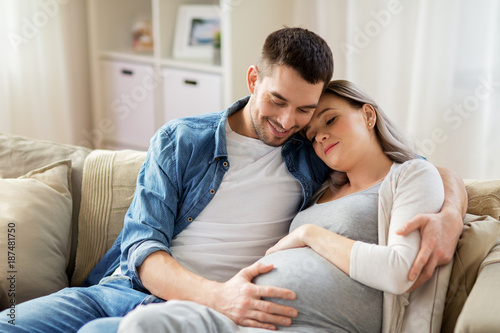 man hugging pregnant woman at home