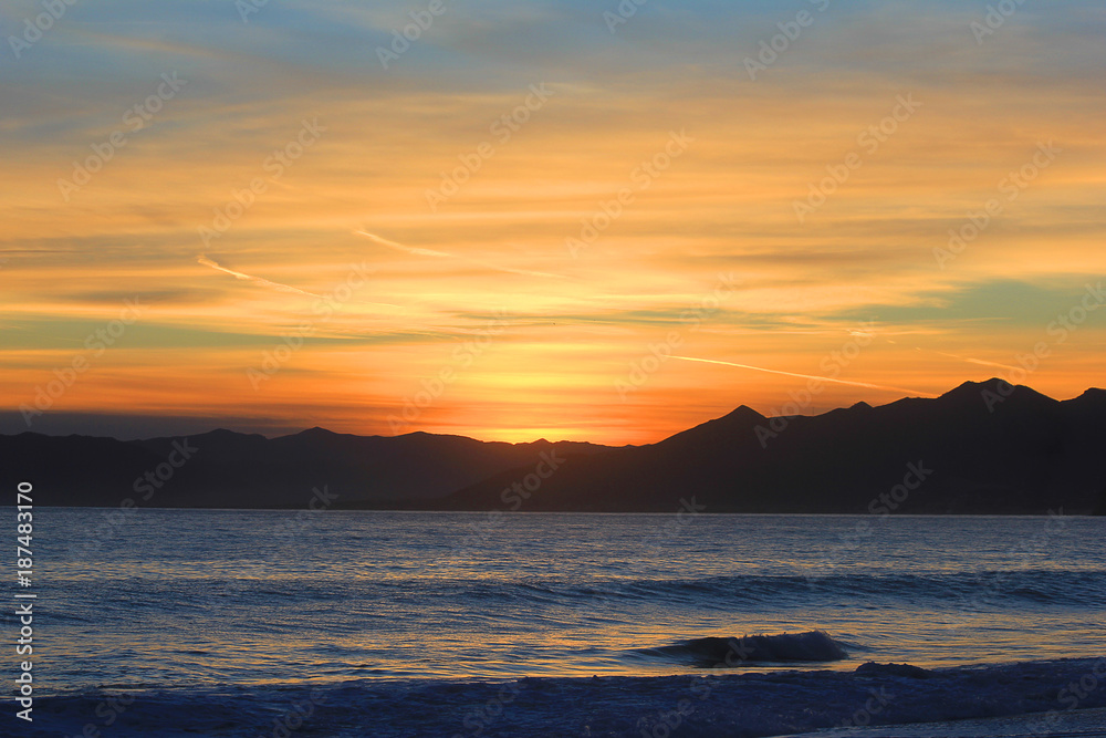 sunset in front of the sea and mountains